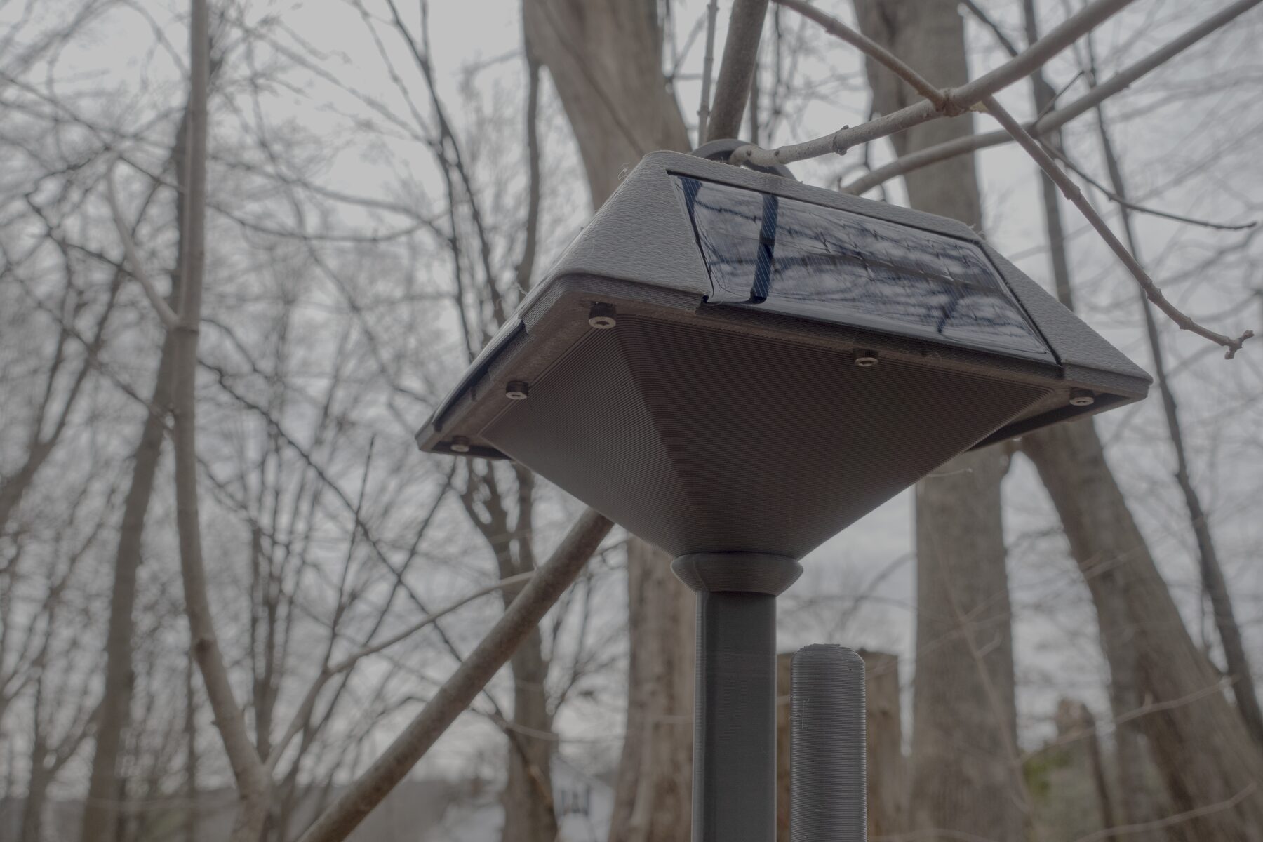 Mounted outdoor overview of the lantern-style MeshCore relay showing the solar panel side and hanging enclosure.